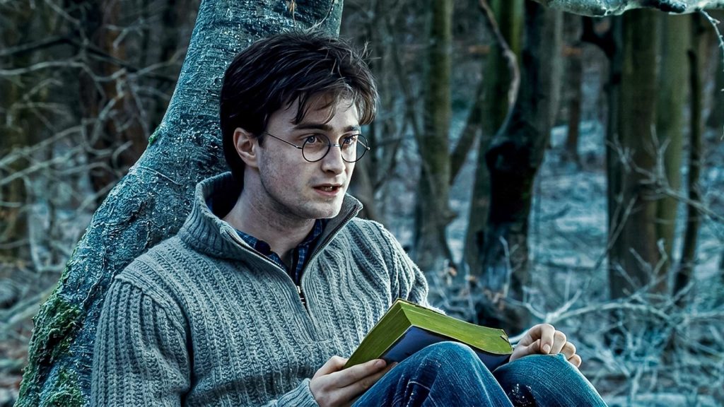 daniel radcliffe as harry potter reading book in snowy forrest in harry potter