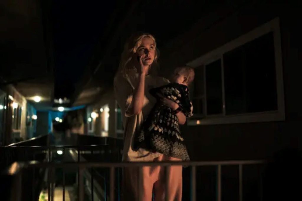 Elle Fanning, holding a baby, in Margo's Got Money Troubles
