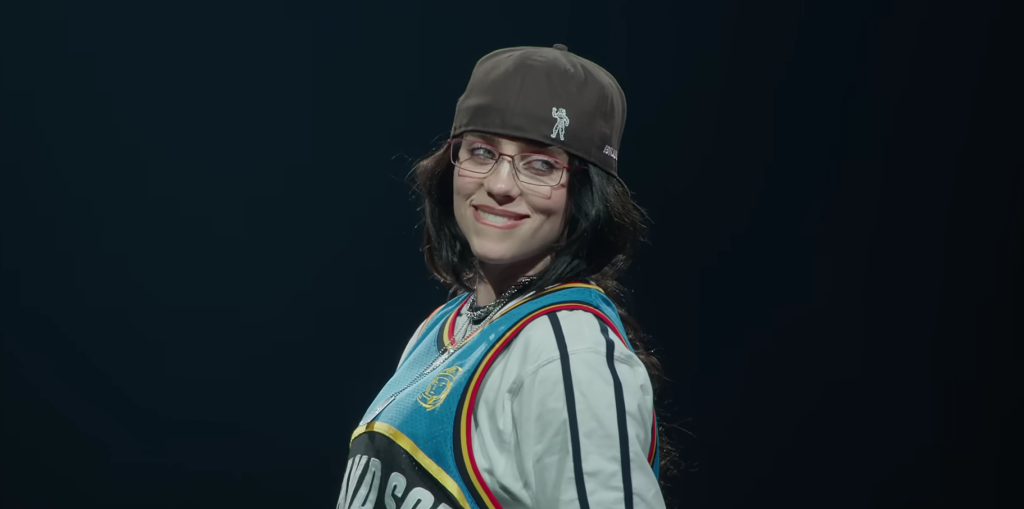 Billie Eilish smiling looking at her fans at a concert in Hit Me Hard and Soft trailer