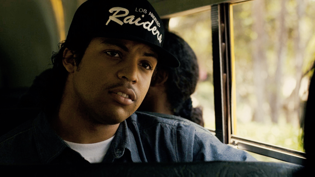 A musician sitting in a vehicle, wearing a cap