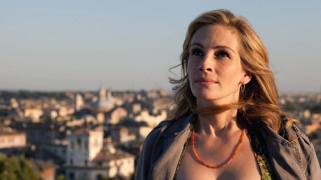 A woman gazes thoughtfully into the distance with a cityscape in the background.