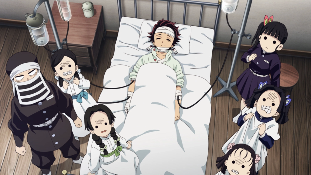 a still from demon slayer where tanjiro is lying on the hospital bed in the butterfly mansion with kanao and other standing around him