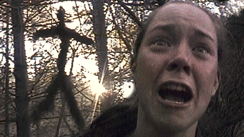 A woman screams after seeing a hung woodoo doll