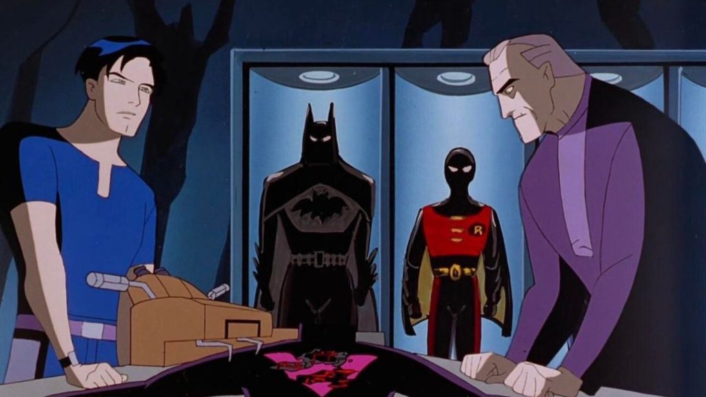 Terry McGinnis and an elderly Bruce Wayne face each other across a Batcave console, with the preserved Batman and Robin suits displayed in glass cases behind them in Batman Beyond