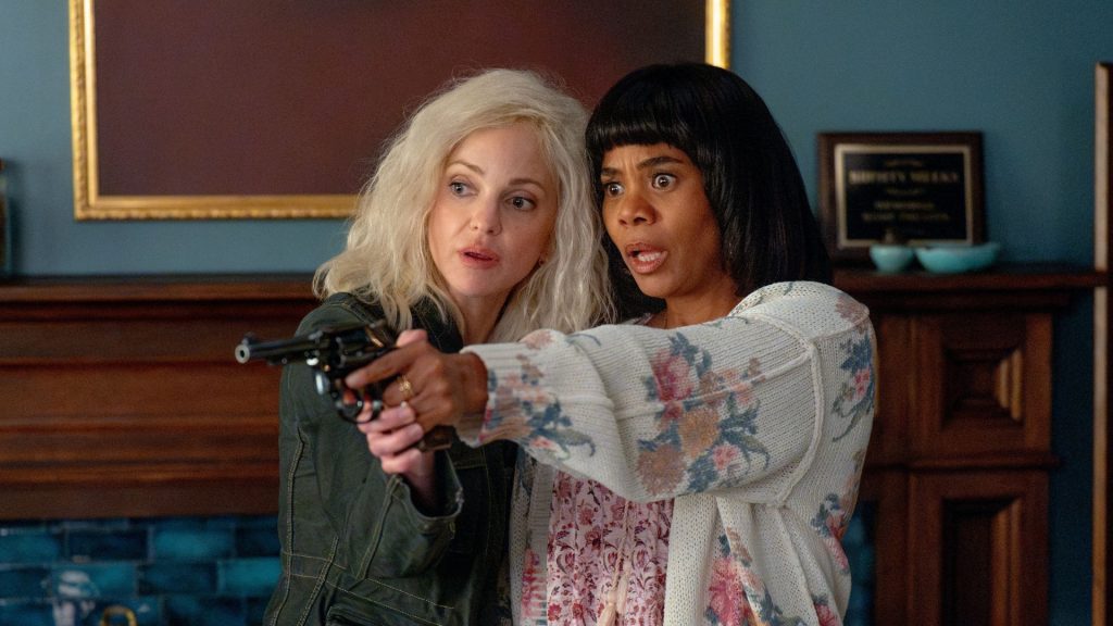 Anna Faris as Cindy Campbell aims a revolver with both hands while Regina Hall as Brenda Meeks stands beside her looking wide-eyed with alarm, in front of a fireplace in Scary Movie 6.