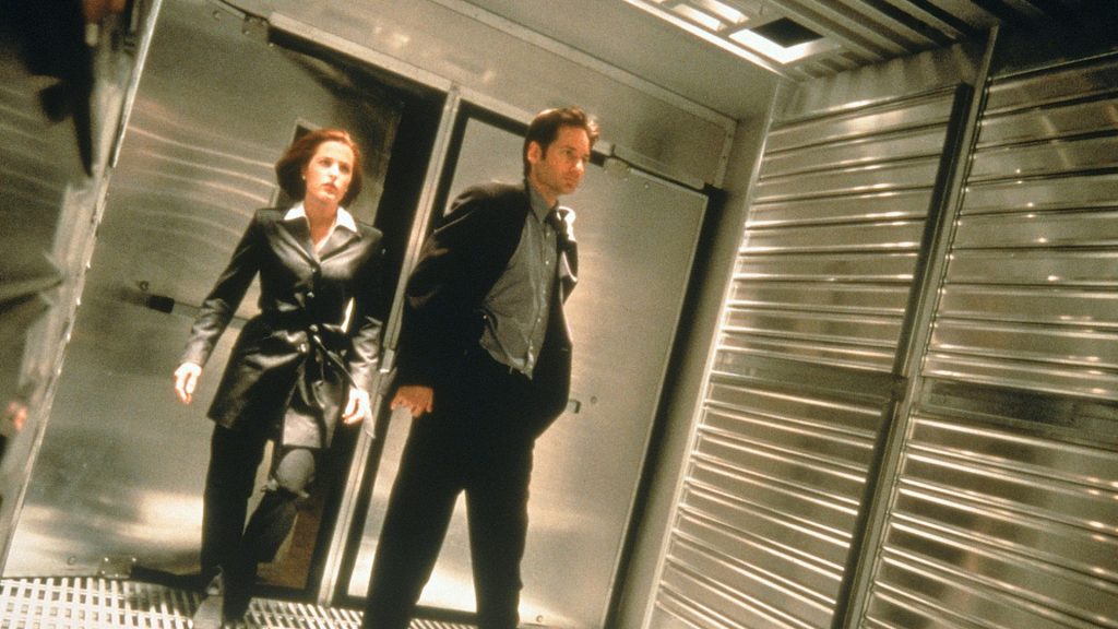  Fight the Future, surrounded by reflective steel walls and illuminated by harsh overhead lighting.