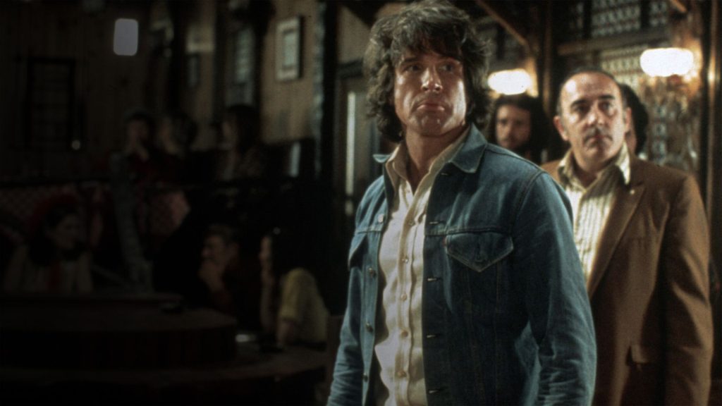Investigative reporter Joe Frady scans a crowded bar in The Parallax View as he follows leads connected to a growing political conspiracy.