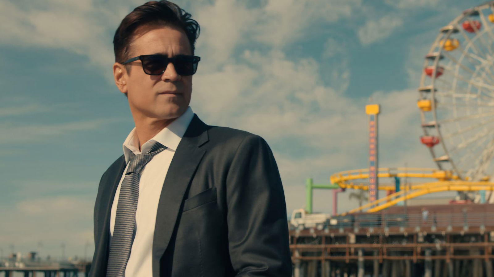 A man in sunglasses looks over a peer on a sunny day