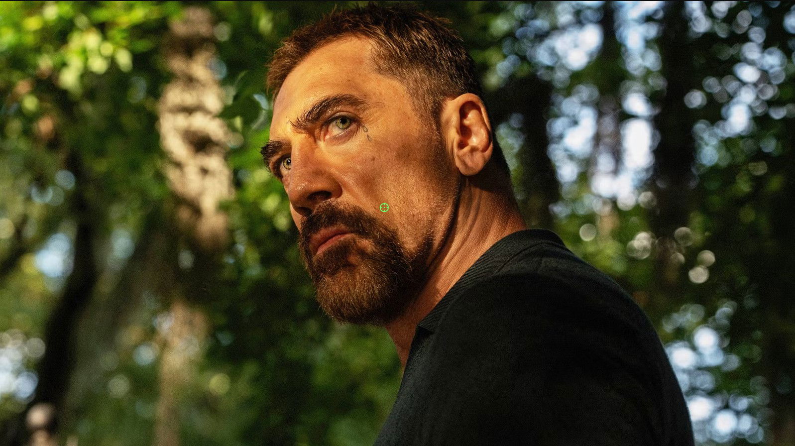 Max Cady looks over his shoulder in a wooded area, his intense expression hinting at the growing danger surrounding the Bowden family