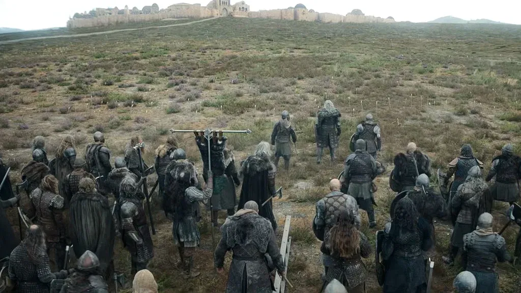 A group of heavily armed Northmen gather on a windswept field in House of the Dragon, facing a fortified settlement as they prepare to join the fighting during the Dance of the Dragons.
