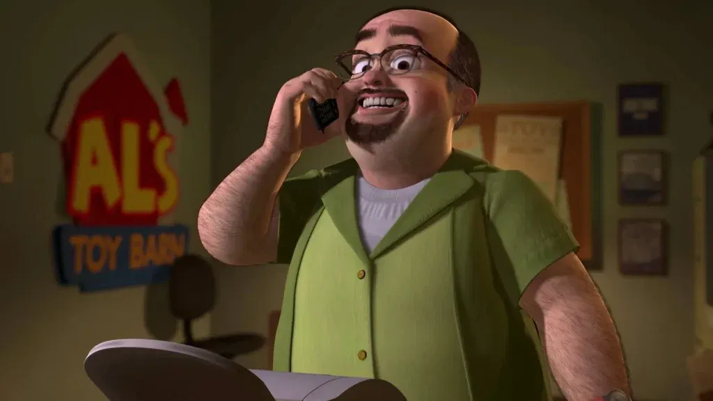 Al McWhiggin, the greedy toy collector from Toy Story 2, smiles while talking on the phone inside his toy store office.