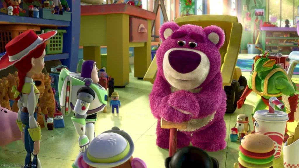 Lotso Huggin’ Bear stands in the middle of Sunnyside Daycare, addressing Buzz Lightyear, Jessie, and the other toys while projecting a friendly appearance.
