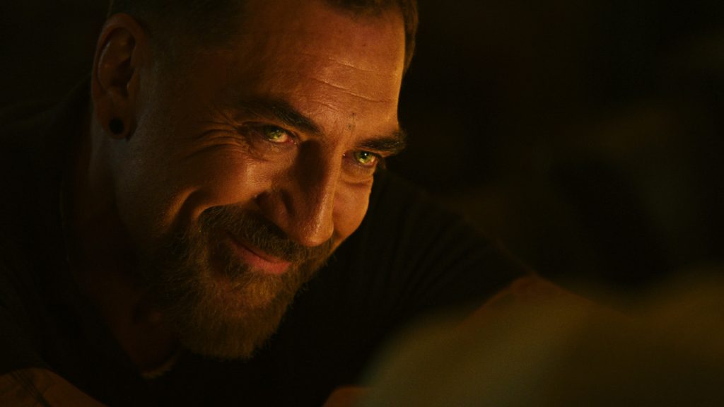Javier Bardem's Max Cady flashes a warm yet unsettling smile during a tense conversation, his piercing gaze hinting at the manipulative charm he uses to disarm his victims in Cape Fear Episode 5.