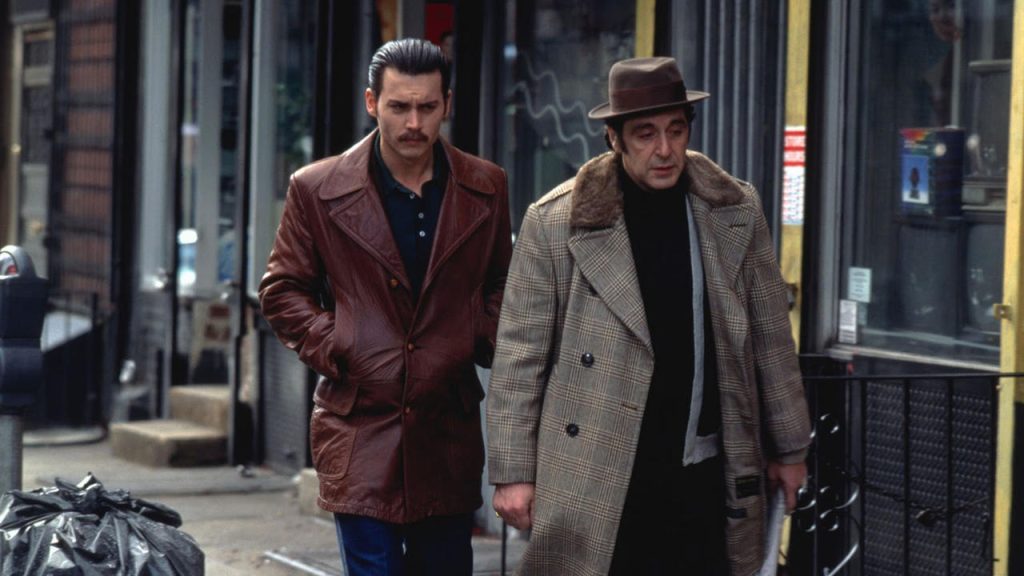 Johnny Depp as undercover FBI agent Donnie Brasco walks beside Al Pacino's aging mobster Lefty Ruggiero on a New York City street in Donnie Brasco (1997).