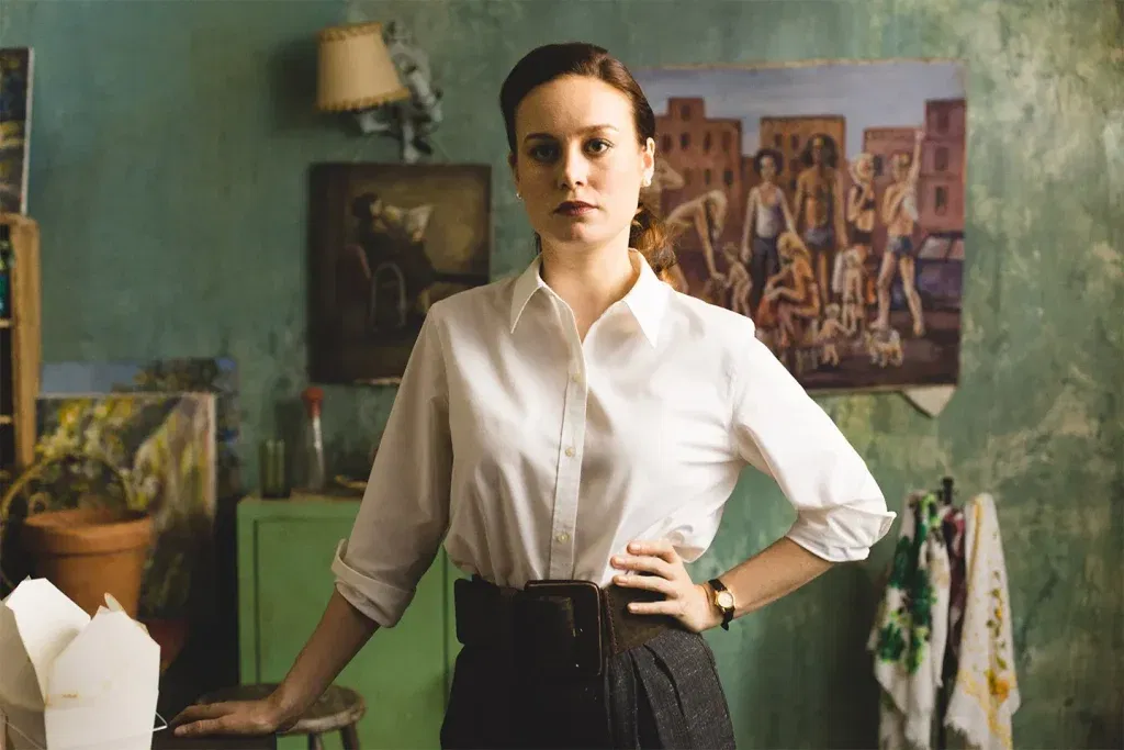 Brie Larson as Jeannette Walls stands with hands on hips in a paint-splattered New York apartment, surrounded by artwork, in The Glass Castle.