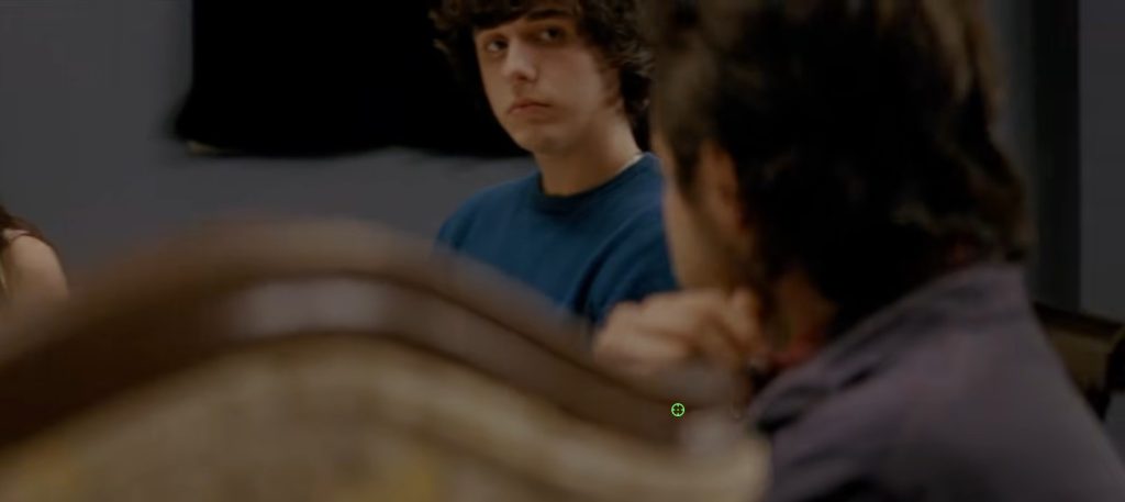 A young man in a blue shirt sits in a classroom scene from The English Teacher (2013)