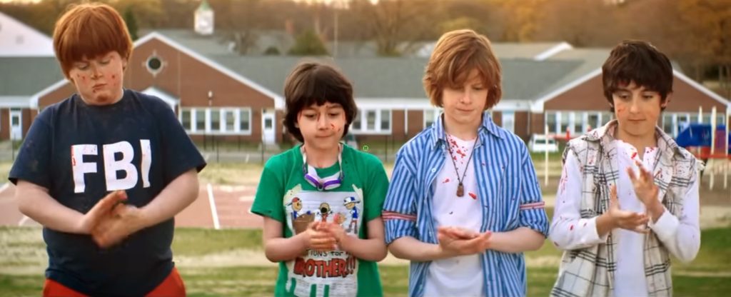 Four kids with blood spatter on their clothes dust off their hands in a scene from Fool's Day (2013)