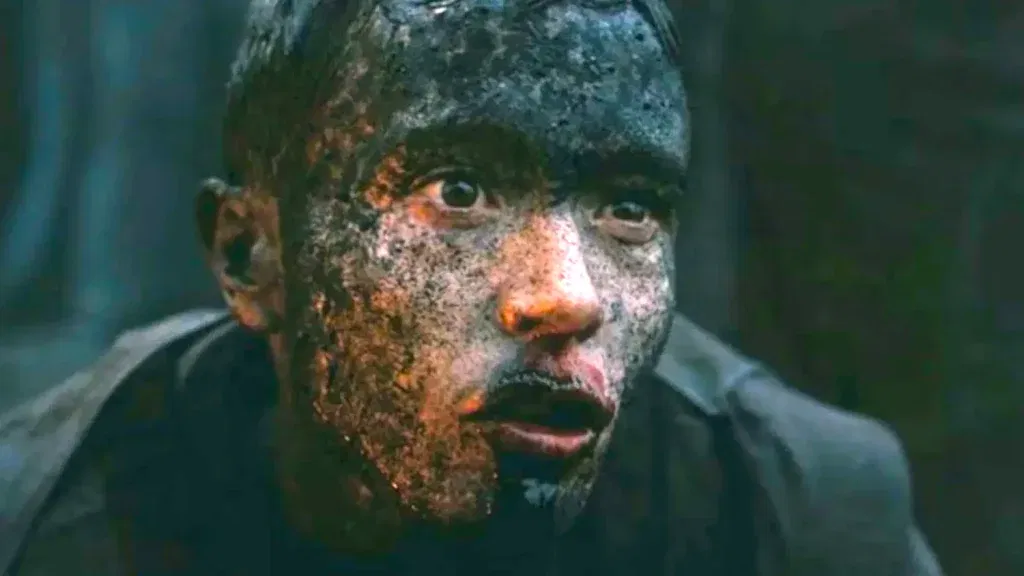 Elliot Page as Sinon, his face blackened with soot and ash, stares in shock in a close-up from Christopher Nolan's The Odyssey.