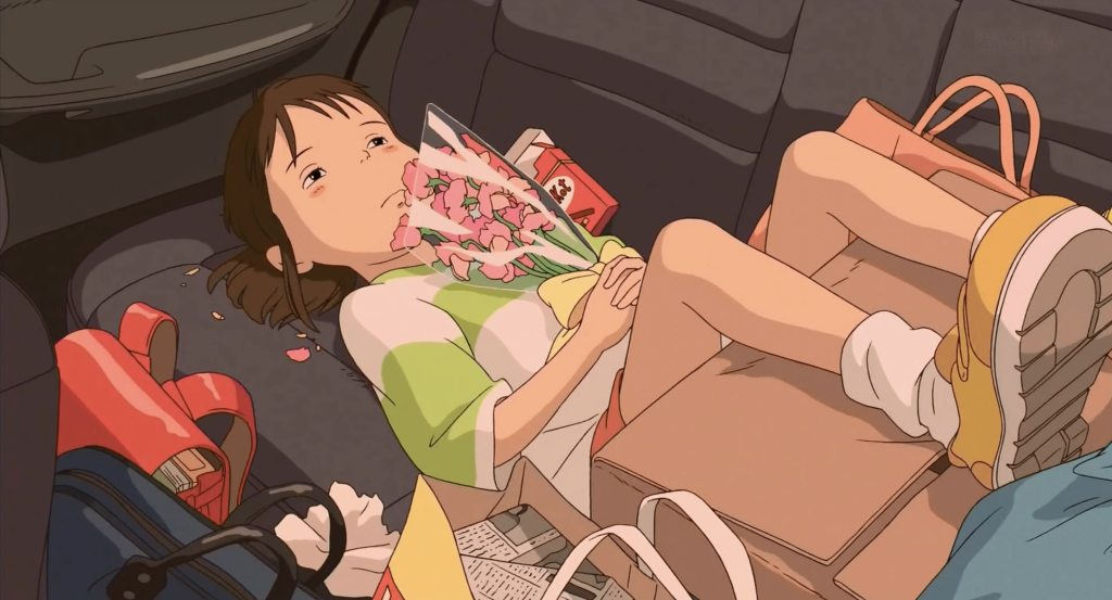 This scene is from the 2001 Studio Ghibli film Spirited Away. The character pictured is Chihiro Ogino. She is shown upset in the back of a car while moving to a new home, holding a bouquet of pink flowers.