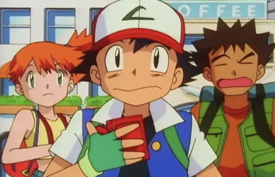 This scene features Ash Ketchum, Misty, and Brock from the Pokémon: Indigo League series. Ash is shown holding his original red Pokédex, a device used to catalog Pokémon data. The group appears to be standing in front of a coffee shop in the Kanto region.