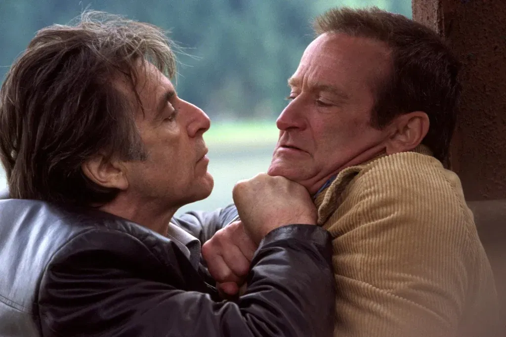 A detective grips a suspect by the collar and pins him against a wall during a tense confrontation in a scene from Insomnia (2002).