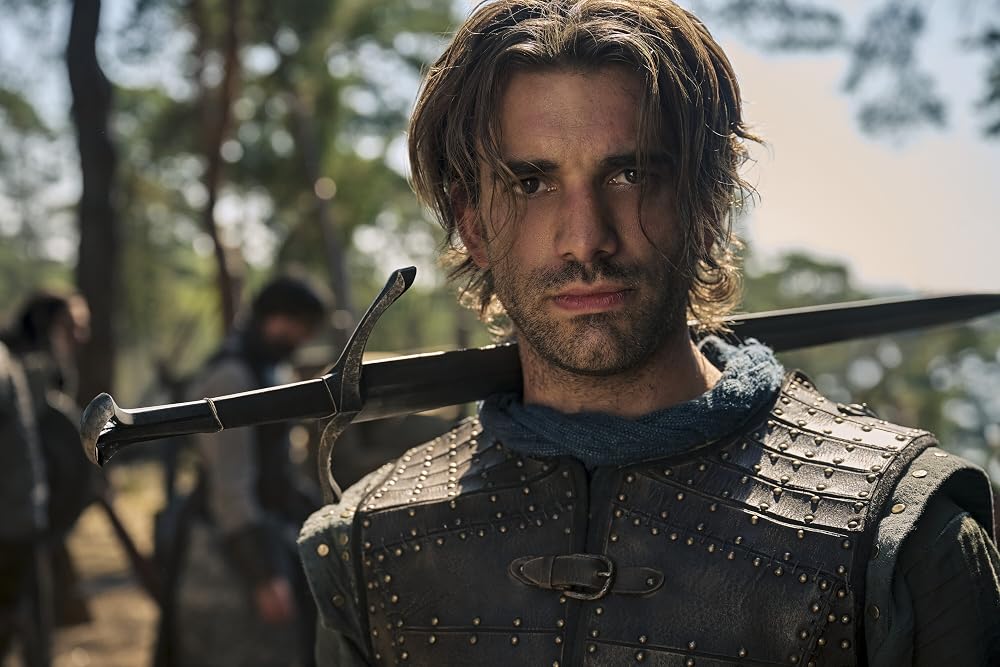  The Rings of Power Season 3, wearing leather armor with a sword resting over his shoulder, standing among a group of soldiers outdoors.