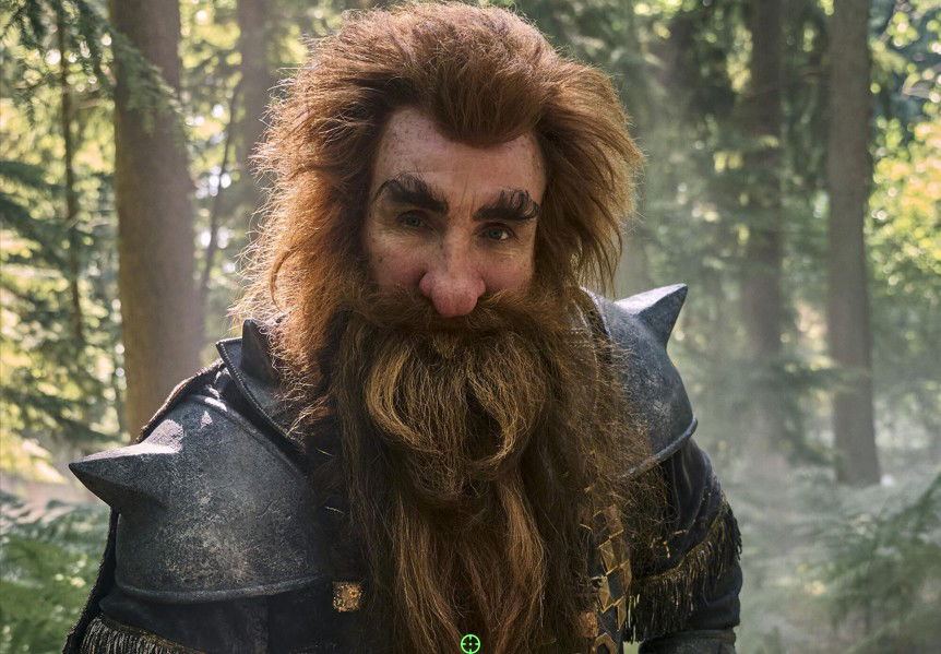  The Rings of Power Season 3, dressed in Dwarven armor with a long braided red beard, standing in a forest.