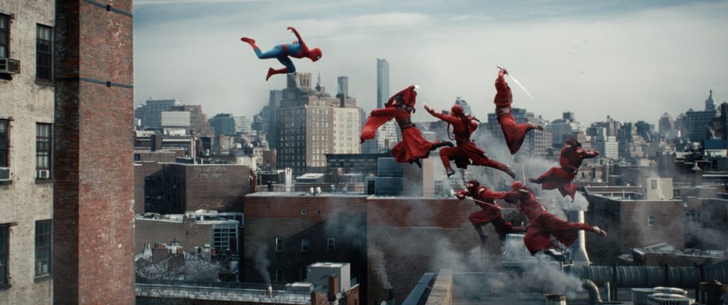 Spider-Man leaps through the air above New York City as several red-clad ninja-like attackers launch a coordinated aerial assault across nearby rooftops.