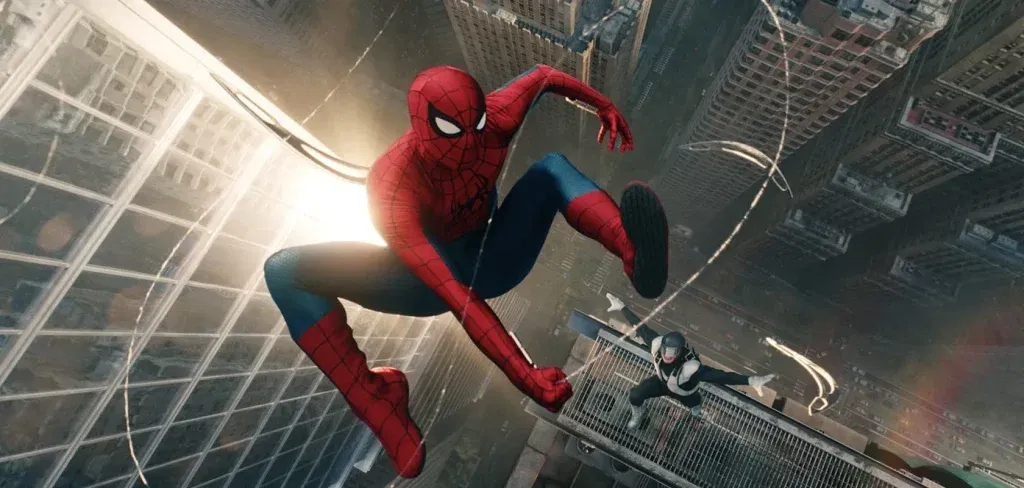 Spider-Man swings high above New York City between towering skyscrapers while a black-and-white-suited villain leaps after him from a rooftop. The dizzying aerial chase unfolds far above the streets below.