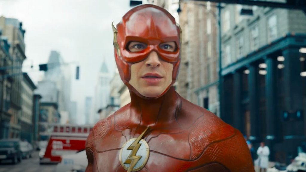 The Flash stands in the middle of a city street wearing his red superhero suit in a scene from The Flash (2023).