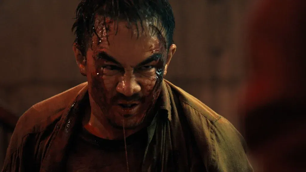 A bloodied and bruised man stares intensely ahead in a close-up from The Furious.