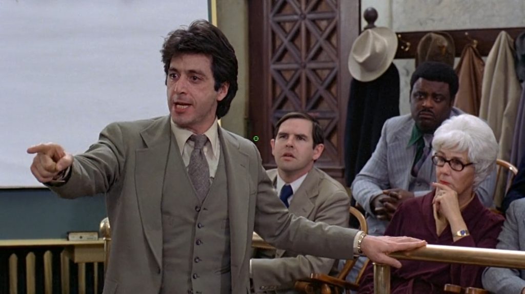 Al Pacino as a lawyer points across a courtroom while making an impassioned argument.