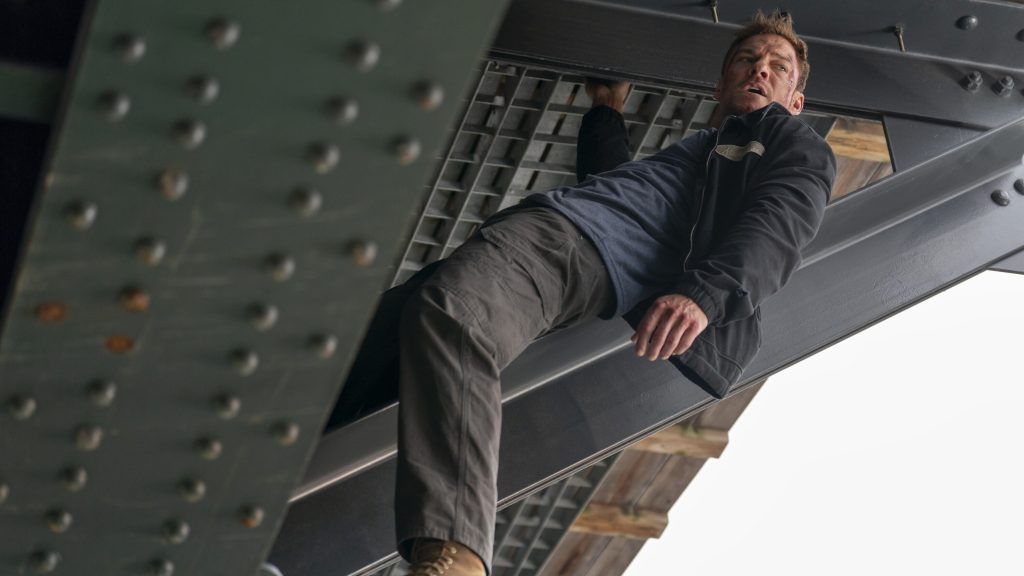 Alan Ritchson hanging off a bridge as Jack Reacher in Prime Video's Reacher.