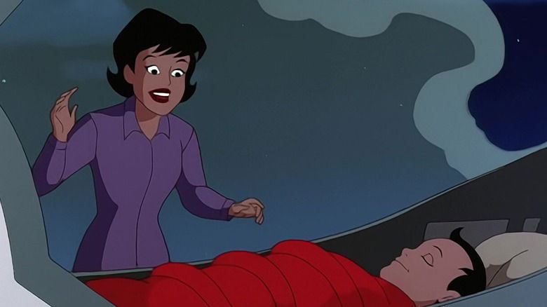 Animated Martha Kent, dark-haired and wearing a purple blouse, reaching toward a young Clark Kent as he sleeps in his ship's wreckage.