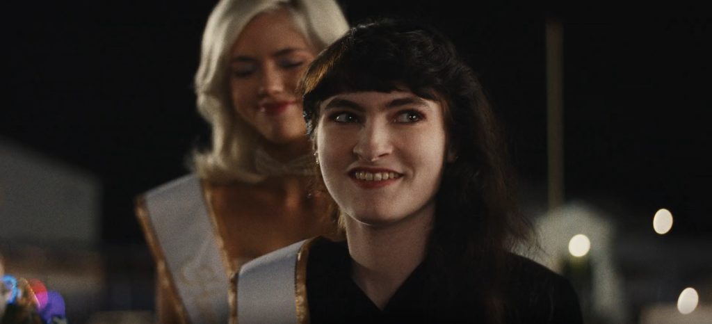 The Shards Episode 6 And 7 Ending Explained: Why Did Rhonda Accuse Susan Of Kidnapping Her? 1 Rhonda smiles wide at a homecoming event while a blonde girl in a white-and-gold sash stands blurred behind her in The Shards.