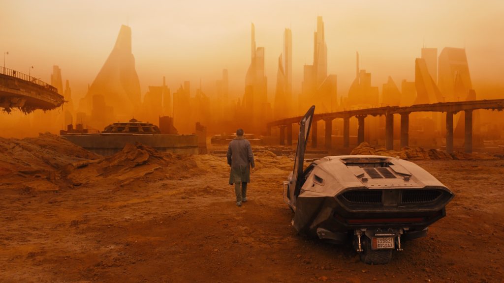 K stands beside his wrecked Spinner in the irradiated ruins of Las Vegas in Blade Runner 2049