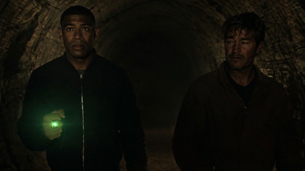 John Stewart's ring glows green as he and Hal Jordan walk through a dark tunnel together in Lanterns episode 4.
