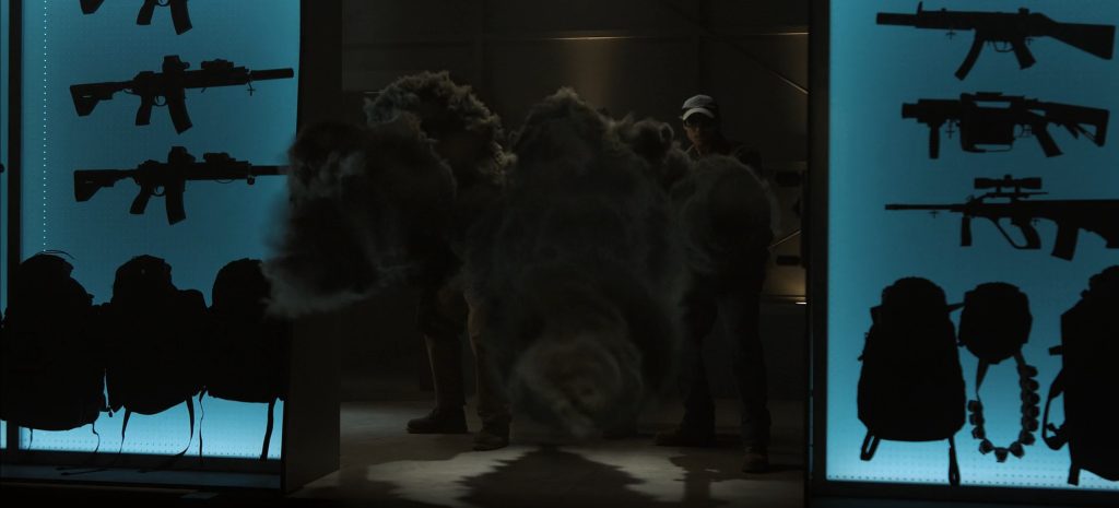 Three shadowy, smoke-like figures stand in a dark armory, guns and tactical gear silhouetted on lit panels behind them, in Lanterns episode 4.