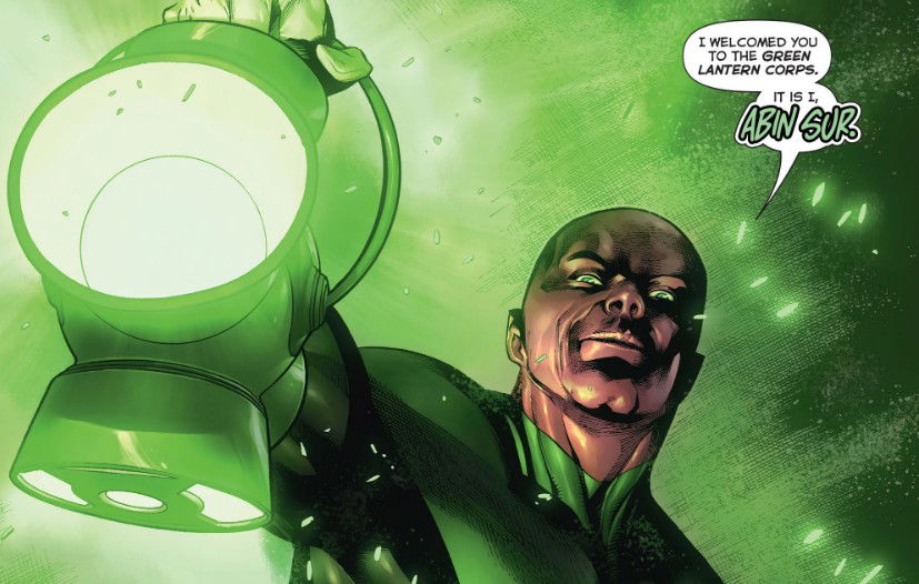 A comic panel showing a bald, bearded alien man with green-tinted skin glowing with energy, speaking from a speech bubble while holding up a glowing green power battery/lantern, introducing himself as the one who bestowed the ring.