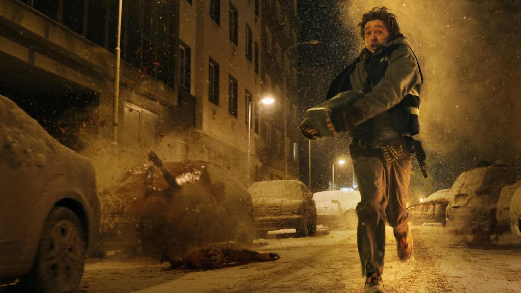 A man running with a parcel in his hands while bodies fall and explode around him in Zach Cregger's Resident Evil.