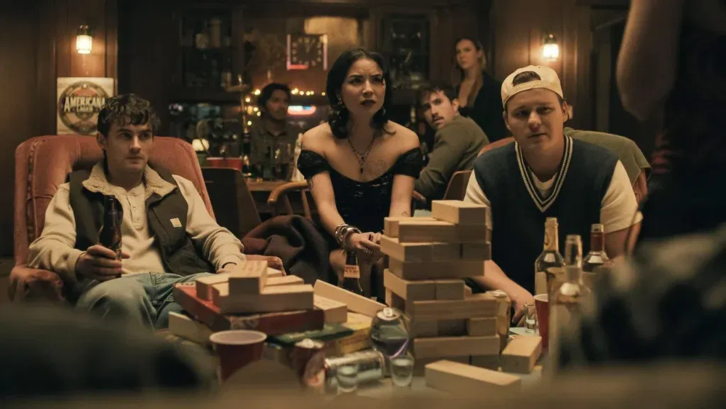 A group of people sitting in a still from Obsession.